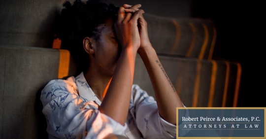 Woman sitting down on floor against the couch with hands on her face