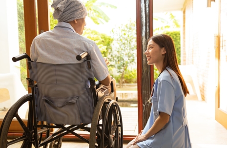 caretaker talking to elder in wheelchair